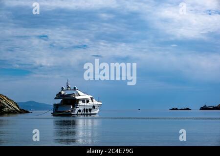 Kea, Otzias, Grèce. Yacht de luxe blanc de couleur ancré près de la terre de l'île de Tzia au milieu de la mer bleue calme. Réflexion du navire, nuageux Banque D'Images