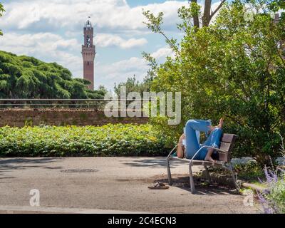 Étudiant sur un banc de parc en bois. Sienne, Italie. Banque D'Images