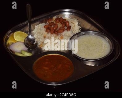 Riz Jeera avec Rajma (curry de haricots) et raita (à base de yaourt) servis sur une plaque d'acier. Banque D'Images