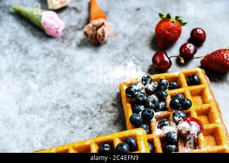 Fond d'aliments sucrés et savoureux avec des fruits rouges et des gaufres, avec l'espace négatif pour la conception d'été. Banque D'Images