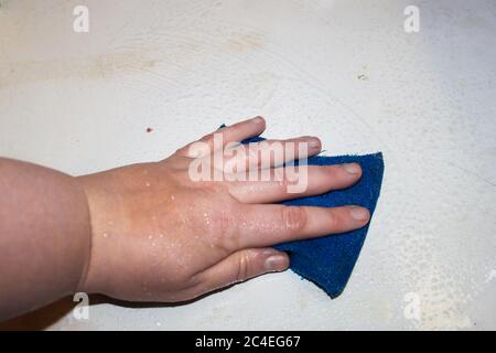Personne nettoyant une plaque avec un nettoyant à vaisselle bleu humide éponge Banque D'Images