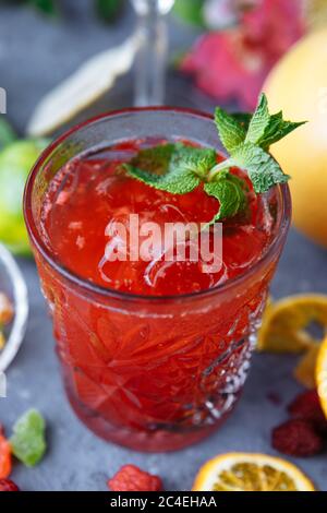 Limonade rose fraîche aux framboises, ornée de feuilles de menthe, d'orange, de lime et de fruits confits sur un fond décoratif Banque D'Images