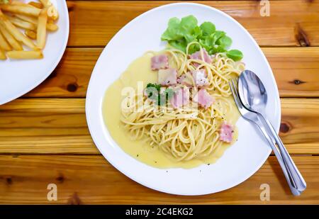 Les spaghetti, fromage frit dans une assiette blanche sur une table en bois. Banque D'Images