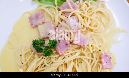 Vue de dessus le spaghetti carbonara avec fromage frit et légumes dans une assiette blanche. Banque D'Images