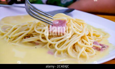 Le spaghetti carbonara au fromage frit dans une assiette blanche sur la table. Banque D'Images