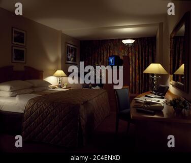 Lampes lumineuses dans la chambre de l'hôtel avec oreillers blancs et draps sur le lit avec courtepointe cintrée Banque D'Images