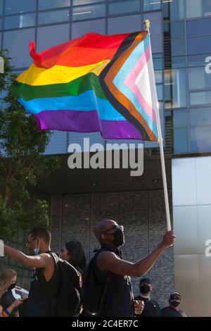 Andrew Ashiofu (Ikechukwu), un immigrant du Nigeria et membre de la communauté LGBTQ+, détient un drapeau de fierté de progrès lors de la Marche tous les Noirs sur South Lake Union à Seattle, le jeudi 25 juin 2020. La marche a été organisée en soutien à la communauté noire LGBTQ+ et en solidarité pour les meurtres de Riah Milton et Dominique Rém'mie et d’autres femmes noires trans. Banque D'Images