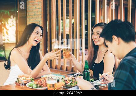 Les amis asiatiques Teeneger se régalent de verres tout en dégustant un dîner dans un restaurant. Banque D'Images