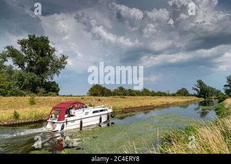 Willingham Cambridgeshire, Royaume-Uni. 26 juin 2020. Un bateau de plaisance navigue le long de l'Old West River pendant que les orages et les nuages d'orage traversent le paysage plat de marais tandis que la vague de chaleur apporte le temps chaud et humide. Crédit : Julian Eales/Alay Live News Banque D'Images