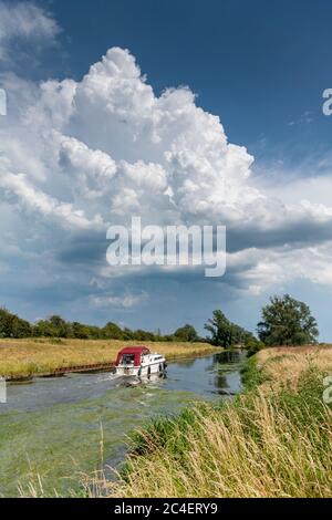 Willingham Cambridgeshire, Royaume-Uni. 26 juin 2020. Un bateau de plaisance navigue le long de l'Old West River pendant que les orages et les nuages d'orage traversent le paysage plat de marais tandis que la vague de chaleur apporte le temps chaud et humide. Crédit : Julian Eales/Alay Live News Banque D'Images