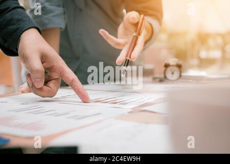 Gros plan sur l'analyse de groupe de jeunes gens d'affaires vers le graphique papier de données sur le bureau dans l'espace de travail. Banque D'Images