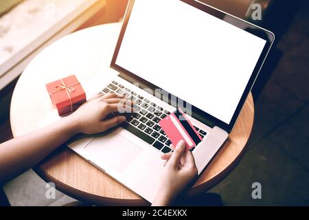 Vue ci-dessus avec la main de femme tenant la carte de crédit faisant des achats en ligne et ordinateur portable écran vide. Banque D'Images