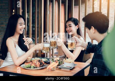 Des amis asiatiques se trinquent avec des verres de bière et s'amusant dans un restaurant. Banque D'Images