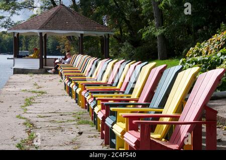 Zoom sur les chaises de Muskoka multicolores situées en bord de mer de la station touristique. Banque D'Images