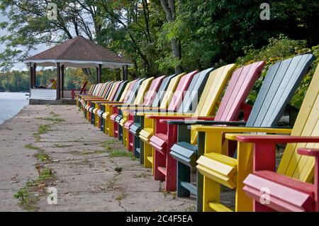 Chaises de Muskoka multicolores au bord du lac de la station touristique avec pavillon de jardin. Banque D'Images