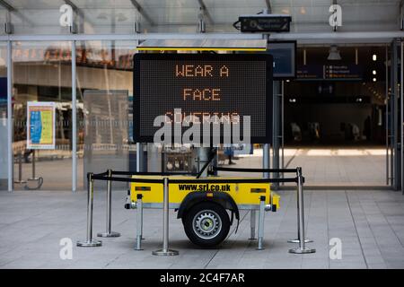 Un panneau numérique avertit les passagers de « porter un masque » à l'entrée de la gare London Bridge, Londres. Banque D'Images