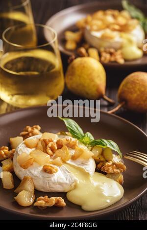 Camembert cuit au four avec poires et noix, servi avec du vin blanc. Banque D'Images