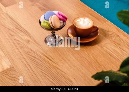 macarons dans un bol en métal et une tasse de café sur une table en bois dans un café Banque D'Images