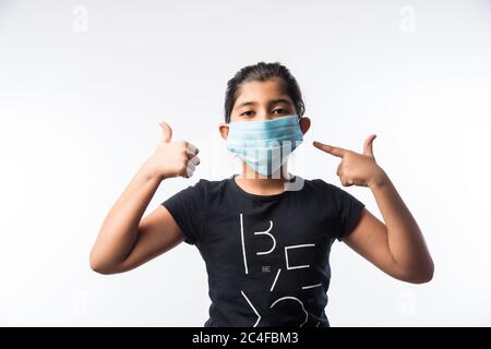 Une fille indienne porte un masque médical pour le visage comme mesure de sécurité contre la pollution ou la propagation du virus, se tenant isolée sur fond blanc Banque D'Images