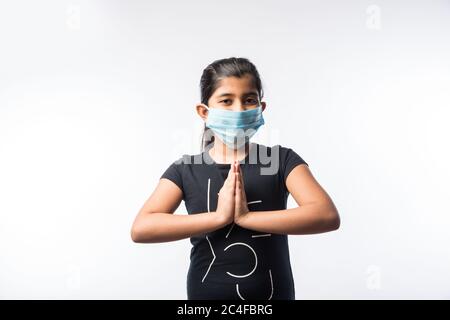 Une fille indienne porte un masque médical pour le visage comme mesure de sécurité contre la pollution ou la propagation du virus, se tenant isolée sur fond blanc Banque D'Images