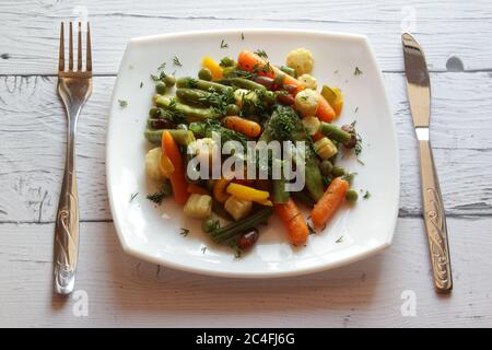 Assiette de légumes sautés sur une table en bois. Vue de dessus. Salade d'été dans un plat blanc. Banque D'Images