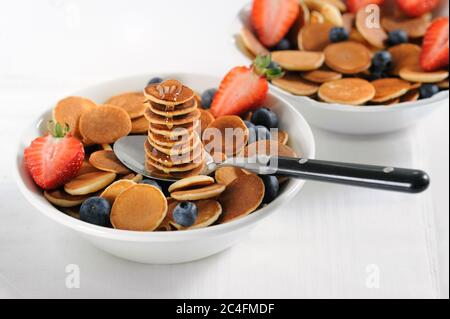 Une pile de crêpes maison sucrée avec du miel, des myrtilles fraîches, des fraises sur fond clair. Espace pour le texte.gros plan.horizontal, sélectif Banque D'Images