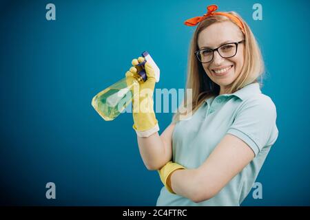 Portrait de femme au foyer dans des gants en caoutchouc à l'aide d'un spray nettoyant Banque D'Images