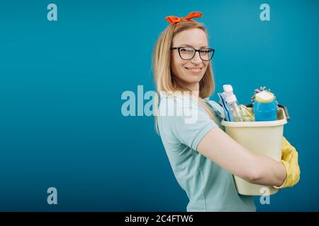 Femme souriante tenant le seau plein de produits de nettoyage Banque D'Images