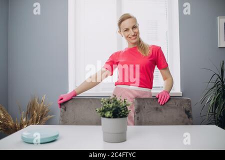 Belle femme en tablier et gants debout sur cuisine confortable Banque D'Images