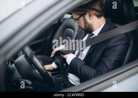 Homme d'affaires assis en voiture et portant la ceinture de sécurité Banque D'Images