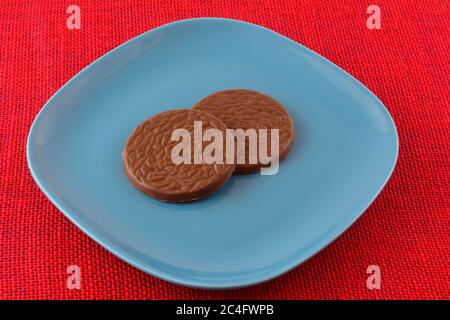 Bonbons au chocolat et à la noix de coco sur une assiette bleue à dessert sur une nappe rouge Banque D'Images