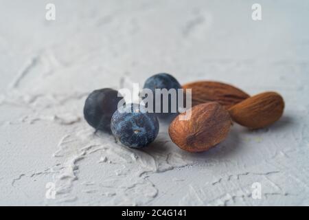 vieux noix d'amandes rastésées avec cinq baies de genévrier bleu au printemps, isolées sur fond blanc texturé. Copier l'espace. Alimentation équilibrée végétalienne saine Banque D'Images