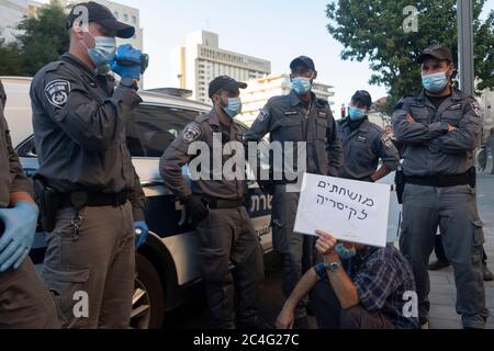 Jérusalem, ISRAËL 26 juin 2020 : des policiers israéliens portant un masque facial en raison de la pandémie du coronavirus COVID-19 entourent un démonstrateur qui porte une pancarte portant la mention « corrompu à Césarée », comme l'ont montré des centaines de partisans du mouvement anti-corruption du drapeau noir devant le domicile du Premier ministre Benjamin Netanyahu, Exigeant sa démission à la lumière des inculpations de corruption qui l'ont été à Jérusalem, en Israël. Crédit : Eddie Gerald/Alay Live News Banque D'Images