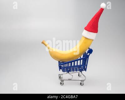 Banane dans le chapeau de Santa sur le mini-chariot du supermarché. Banque D'Images