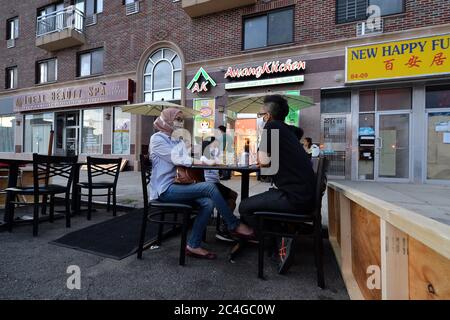 New York, États-Unis. 26 juin 2020. Portant des masques à l'époque de la COVID-19, la famille Sukarmadijaya s'assoit en plein air à une table qui s'est établie devant le trottoir devant Awang Kitchen, un restaurant indonésien le long du Queens Boulevard, dans la section Elmhurst de Queens, NY, le 26 juin 2020. Dans le cadre de la phase II, les restaurants peuvent servir les clients aux tables de trottoir et à 8 pieds dans la rue du trottoir, tous destinés à prévenir la propagation de la pandémie COVID-19. (Anthony Behar/Sipa USA) crédit: SIPA USA/Alay Live News Banque D'Images