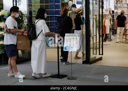 Les clients utilisent un désinfectant pour les mains avant d'entrer dans Uniqlo Tokyo, un nouveau magasin à Marronnier Gate Ginza, après la levée de l'état d'urgence du coronavirus. Banque D'Images