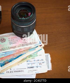 Objectif de la caméra, argent étranger et carte d'embarquement sur une table en bois. Tourisme, vacances, équipement de photographie de voyage. Banque D'Images