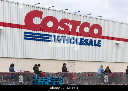 Logo Costco Wholesale sur un magasin alors que les clients attendent en ligne pendant la pandémie mondiale du coronavirus COVID-19. Banque D'Images