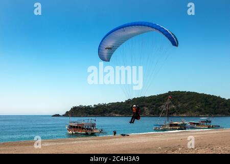 Un parapente débarque sur la plage d'Oludeniz sur la côte Turquoise de Turquie. Oludeniz est une station balnéaire située à proximité de la ville côtière de Fethiye. Banque D'Images