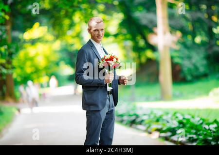 portrait du marié tenant un bouquet dans le parc Banque D'Images
