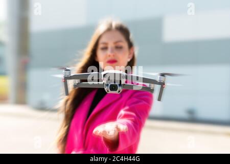 des terrains de drone sur la main, jeune femme défoqué en arrière-plan, se concentrent sur le quadricoptère Banque D'Images