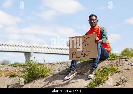 Portrait de jeunes volontaires africains assis sur le sol avec un écriteau à l'extérieur Banque D'Images