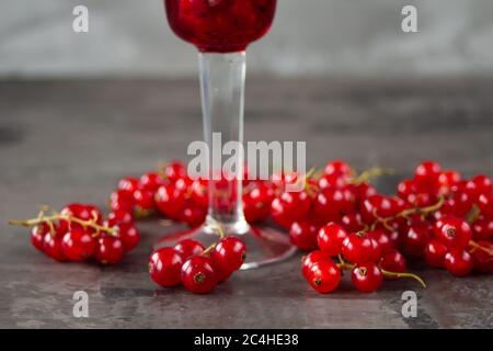 Cassis dans un verre à grenaille, le reste est dispersé autour d'elle sur un fond gris texturé. Photo de haute qualité Banque D'Images