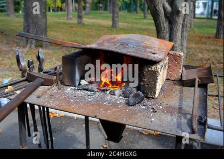 À l'atelier smithy. Pinces, marteau et forge à brûler pour le travail Banque D'Images