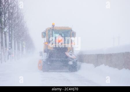 Chasse-neige véhicule de camion déneigement en cas de tempête de neige ou de tempête de neige. Nettoyage urgent de la rue à la lumière du jour. Chute de neige à la ville européenne. Hiver Banque D'Images