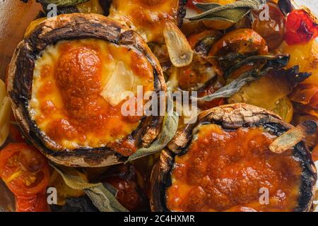 Portobello cuit au fromage cheddar, tomates cerises et sauge dans une marmite en verre sur fond de béton blanc vue de dessus de près Banque D'Images