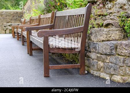 Vue abstraite des bancs de parc vides vus après une douche à effet pluie. Le jardin bien entretenu est visible en arrière-plan. Banque D'Images