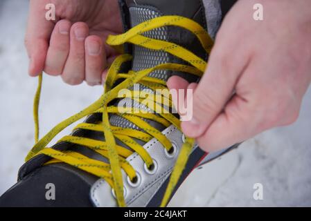 Un homme qui enferme des patins dans la neige en hiver, gros plan Banque D'Images