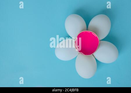 Une fleur de cinq œufs blancs et un œuf cassé avec de la peinture rose à l'intérieur. Banque D'Images