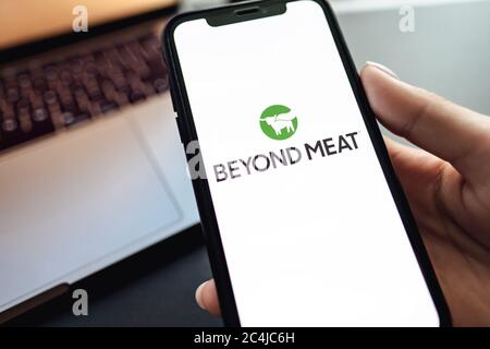 Mains tenant l'iPhone X avec le logo Beyond Meat sur l'écran. Banque D'Images